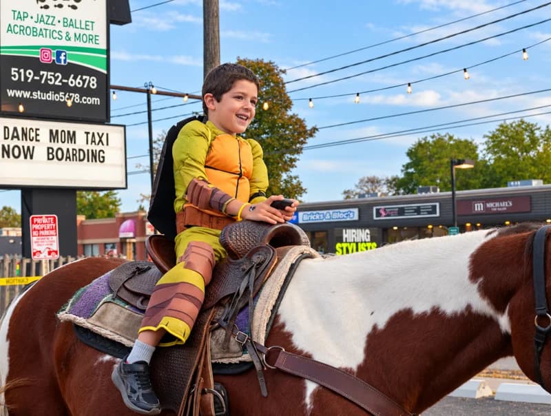 A child in a turtle costume rides a brown-and-white pony.
